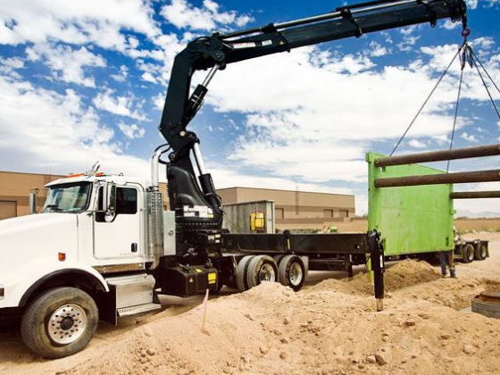 A truck crane lifting a green panel at a construction site