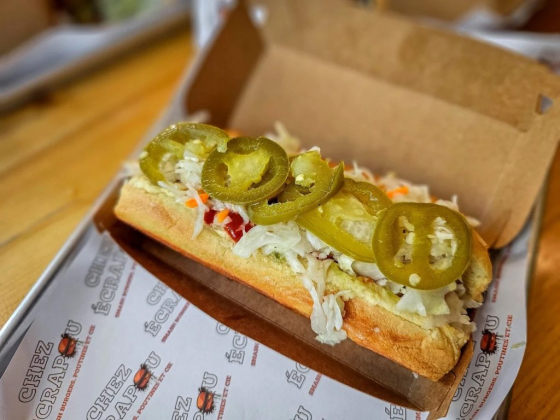 Hot dog topped with jalapeños and slaw on a table