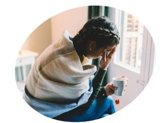 Wrapped in a blanket holding a mug indoors