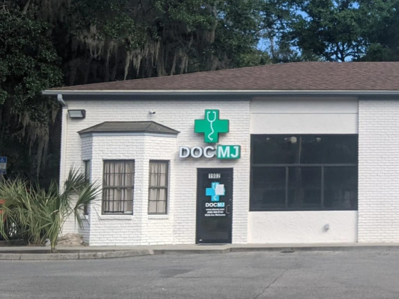Front of white brick medical clinic with DOC MJ sign