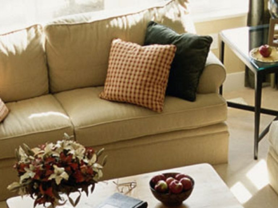 A sunny living room with a beige sofa and wooden table