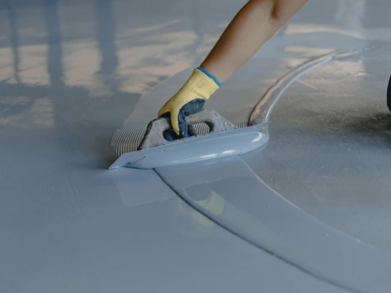 Gloved hand applying epoxy resin on a floor surface