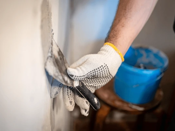 Worker smooths wall with plaster using a spatula