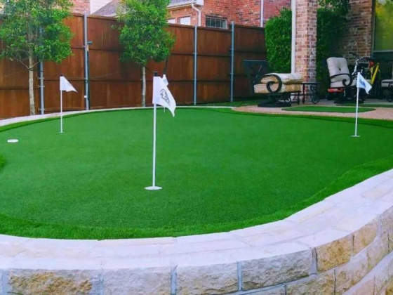 A neatly designed backyard putting green with flags and lawn chairs