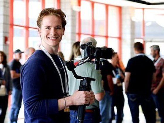 Smiling person with camera rig at gathering