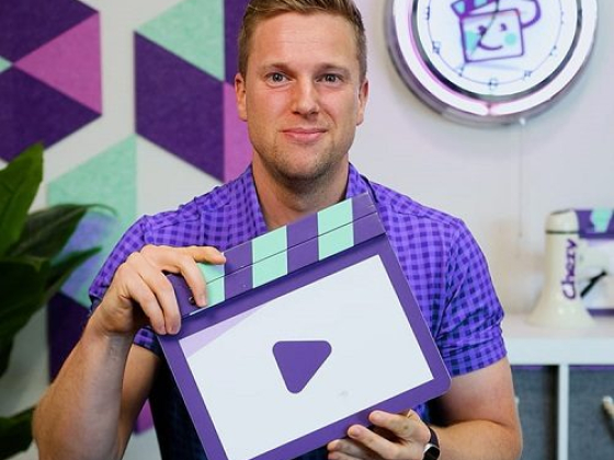 Smiling man in purple shirt with clapperboard